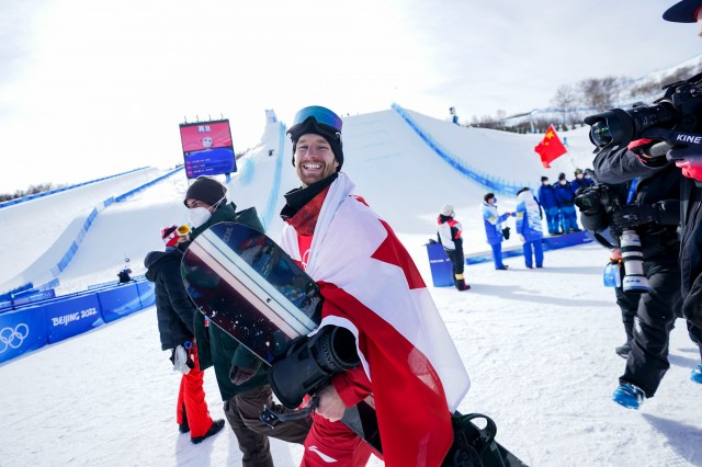 An athlete looks over at the camera with a smile as he walks 